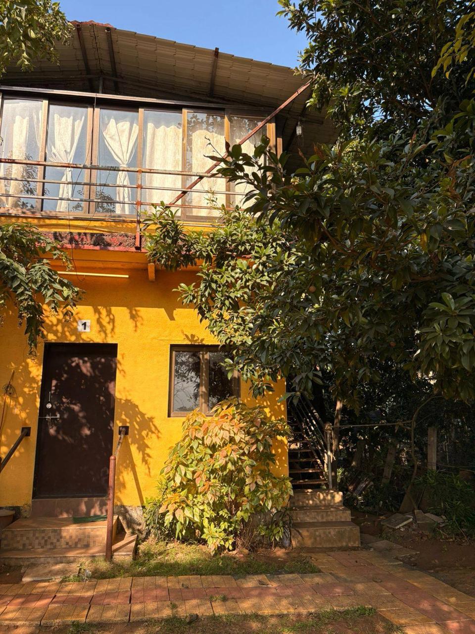 Comfortable yellow farm cottage facade nestled in Wada's lush greenery